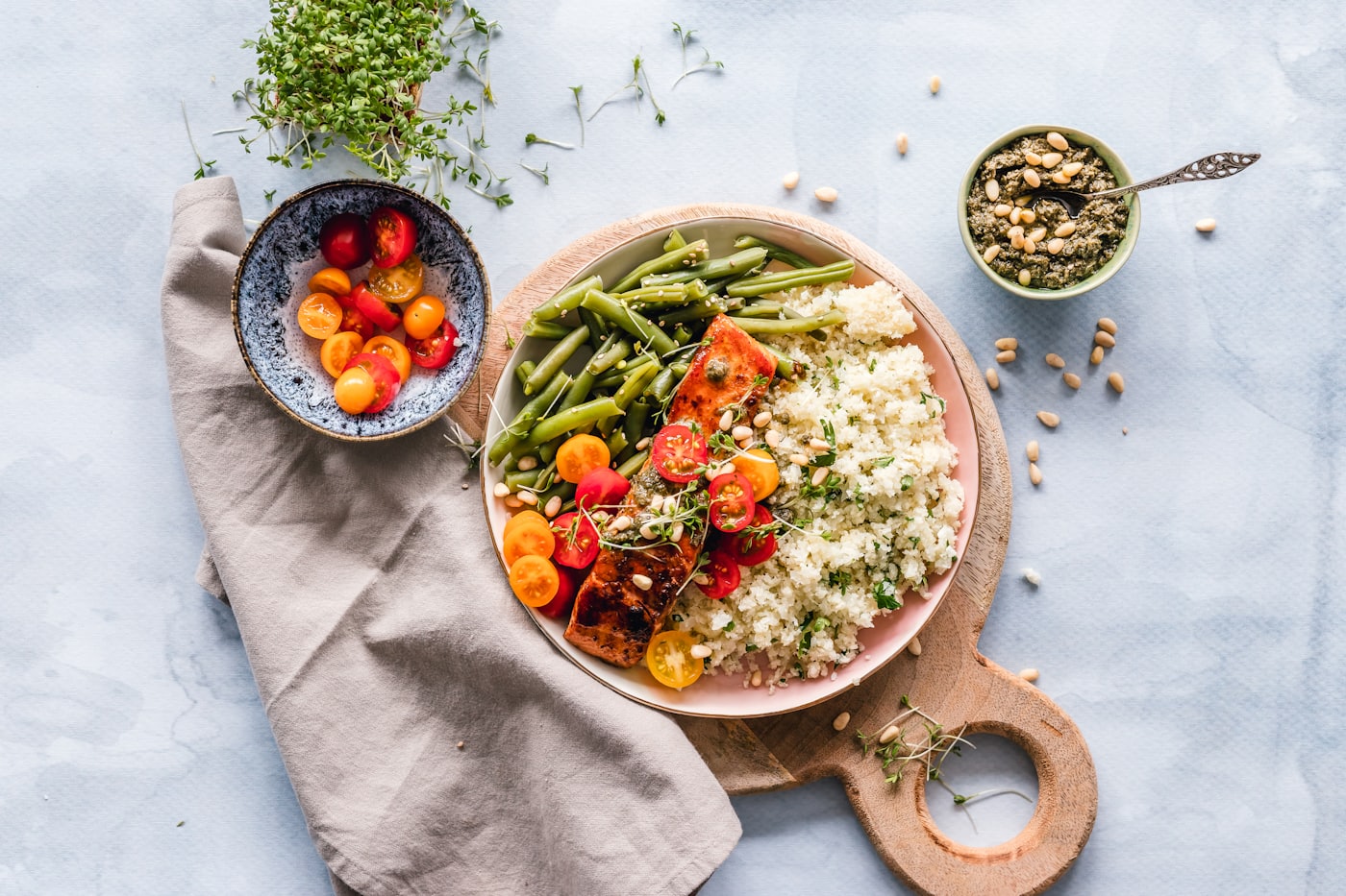 Bunte Bowl mit Quinoa, grünen Bohnen, Kirschtomaten und Kräutern auf hellem Leinen